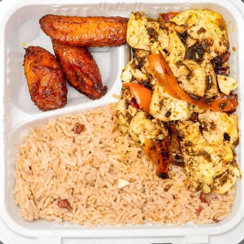 Jamaican jerk chicken with rice and peas, and fried plantains in a white takeout container.